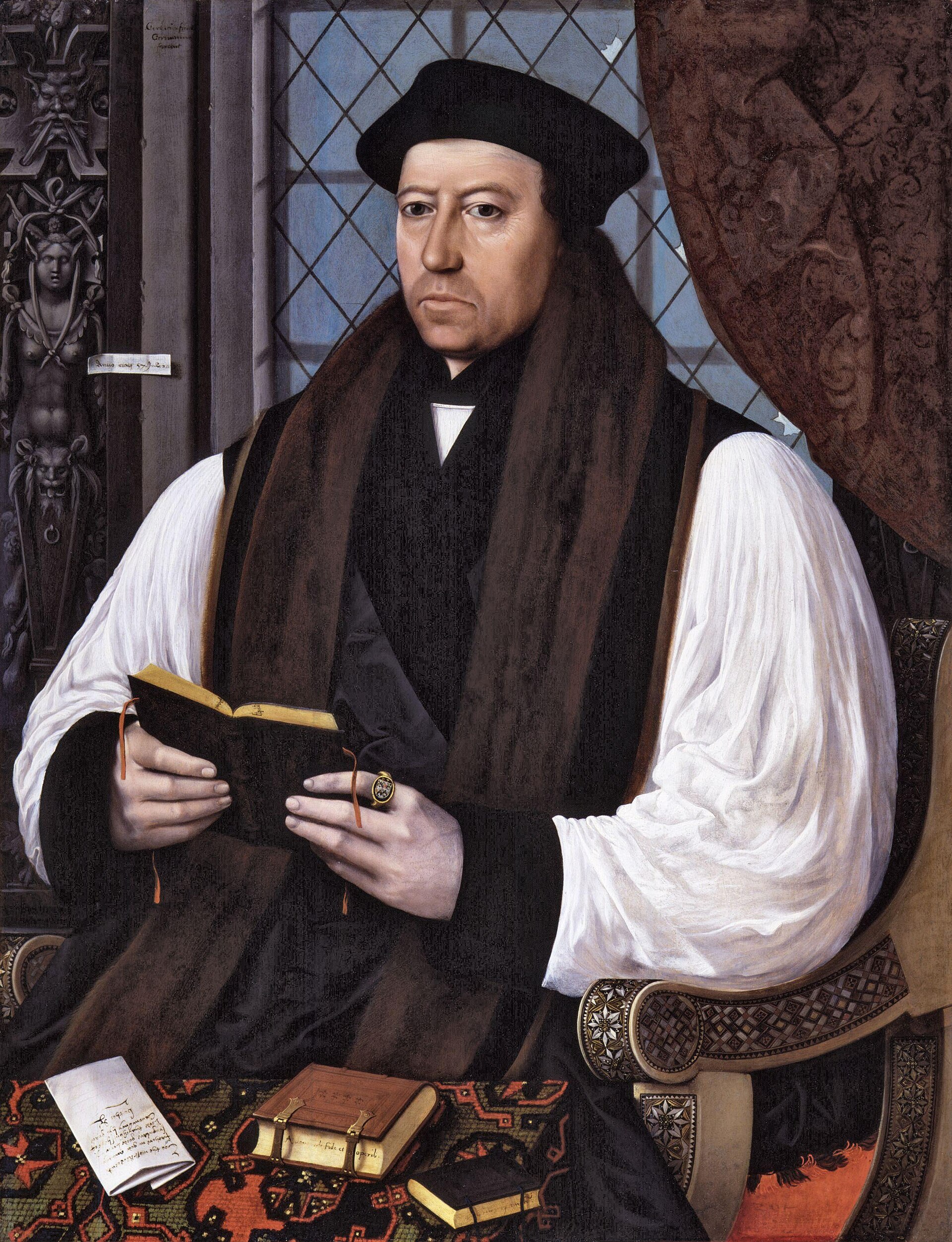 Portrait of a clean shaven man in a black cap and white clerical robe with black sleeves, seated, holding a book, a window behind him