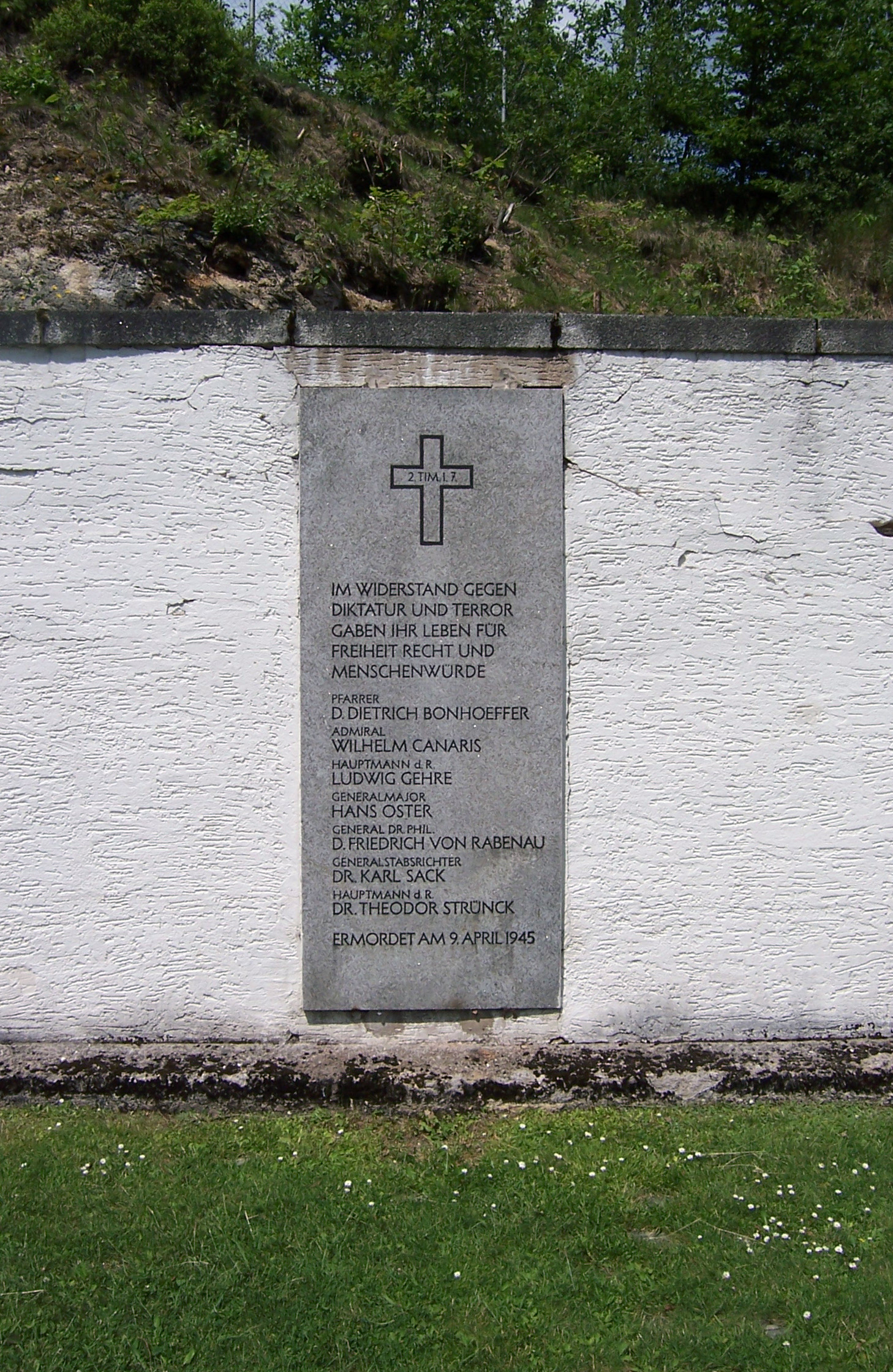 Stone memorial plaque on a wall with names of executed resistance members and a German inscription
