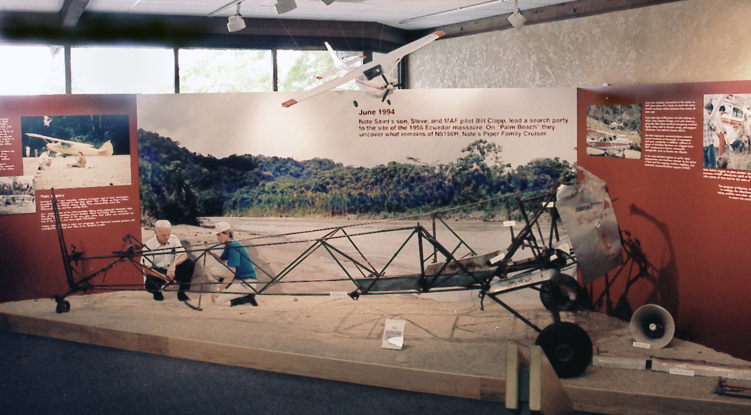 The bare metal frame of a small high-winged aircraft displayed indoors, without skin on the fuselage