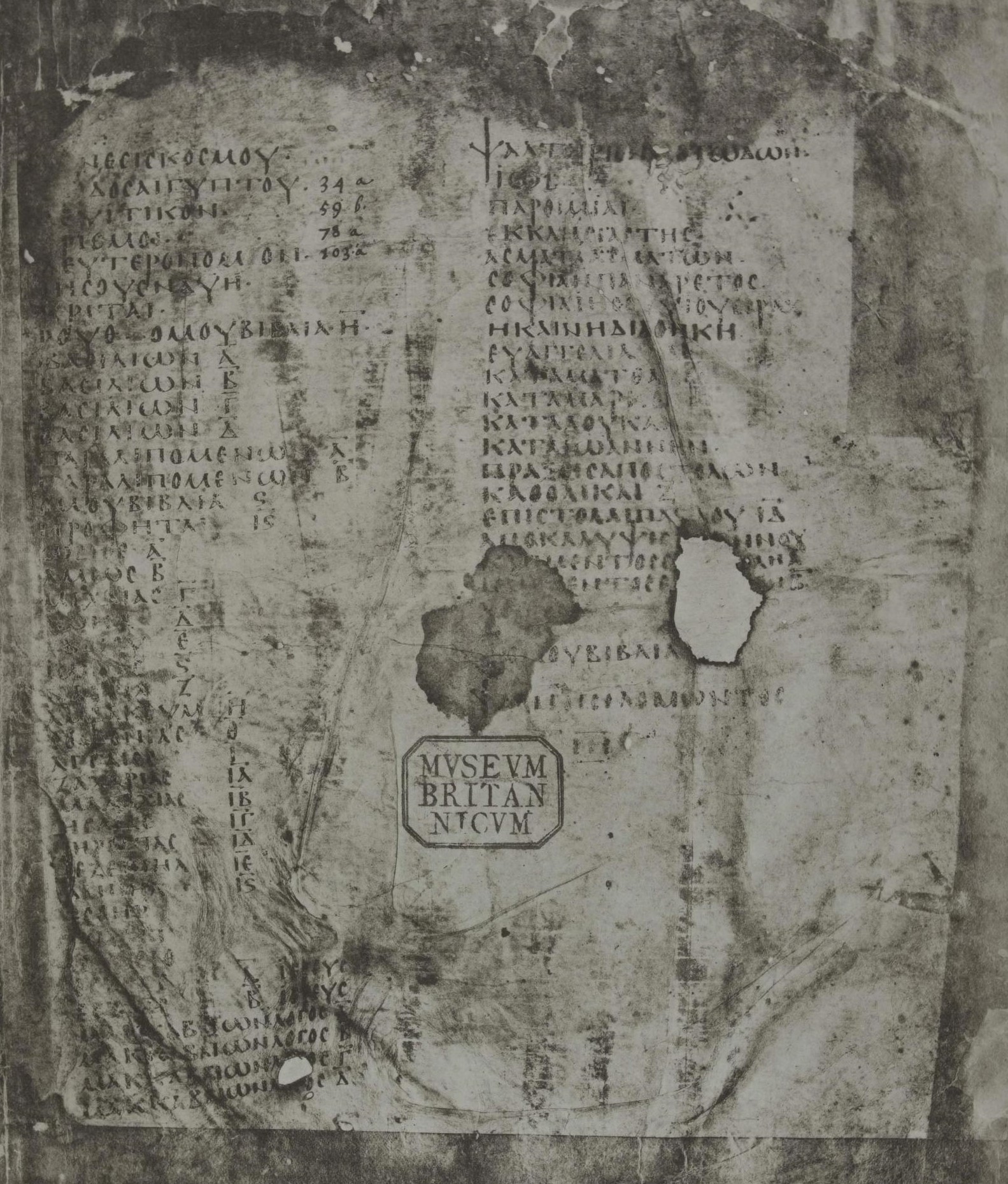 A black and white facsimile of a parchment page with two columns of Greek capital letters listing book titles, with ornamental marks between the entries