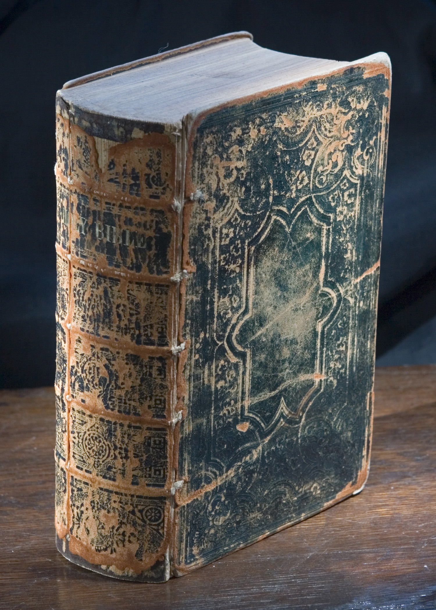 A thick old leather-bound family Bible with worn edges and a clasp, photographed closed