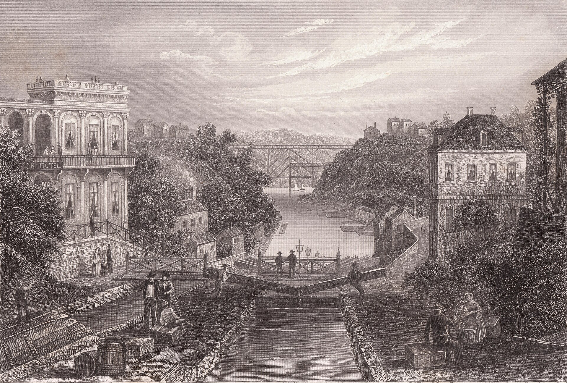 Lithograph of a canal running through a town with stone locks stepping up a slope, canal boats in the water, and brick buildings on both banks
