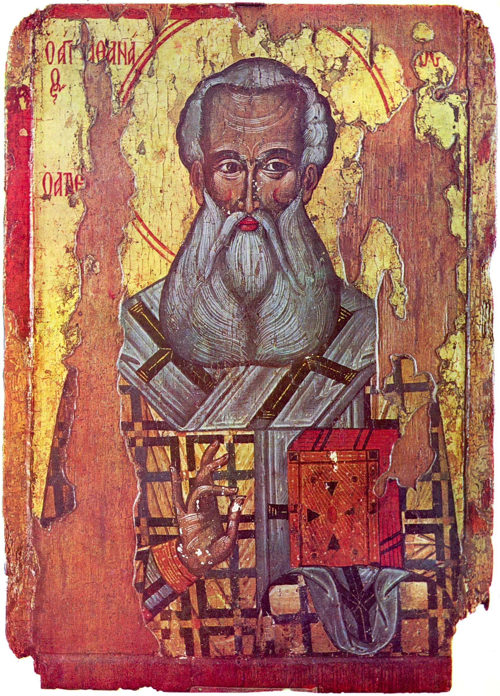 Worn painted icon on wood of a bald, white-bearded bishop with a halo, wearing a vestment patterned with black crosses and holding a red book, with paint flaking around the edges