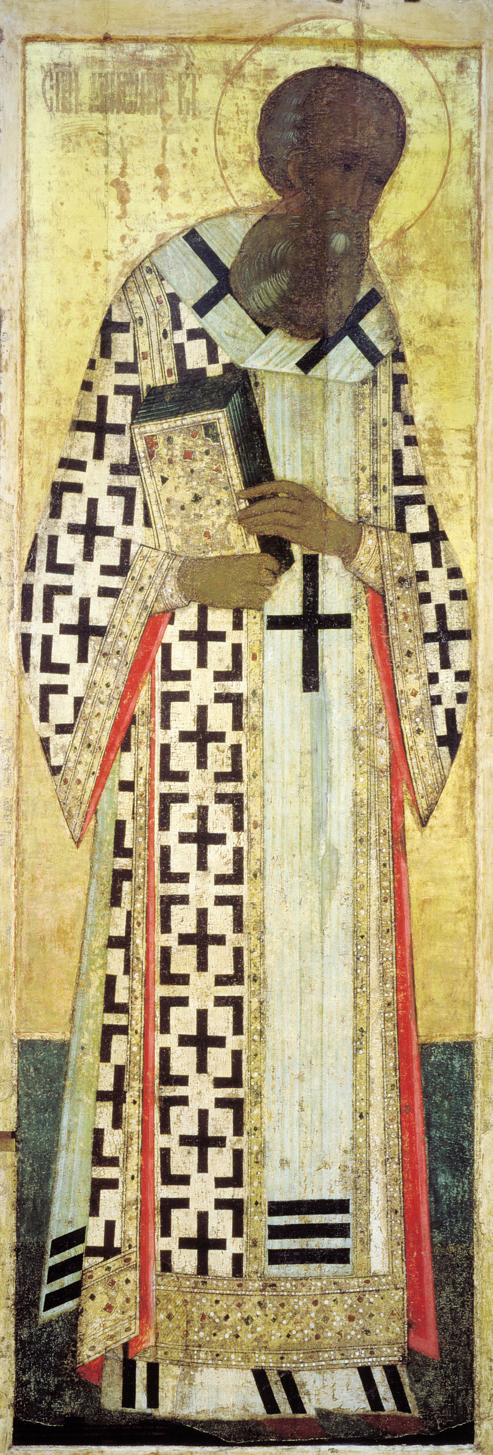 A tall, narrow icon of a bearded bishop in a white robe covered with black crosses, holding a closed book and turning slightly to his right against a gold background.