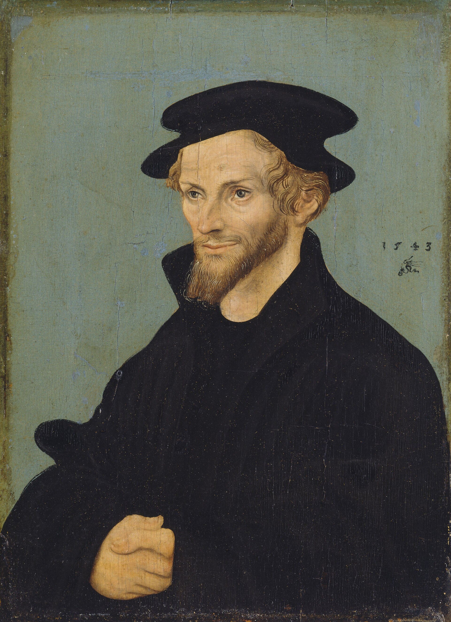 Half-length portrait of a thin bearded man in a dark coat and cap against a plain background
