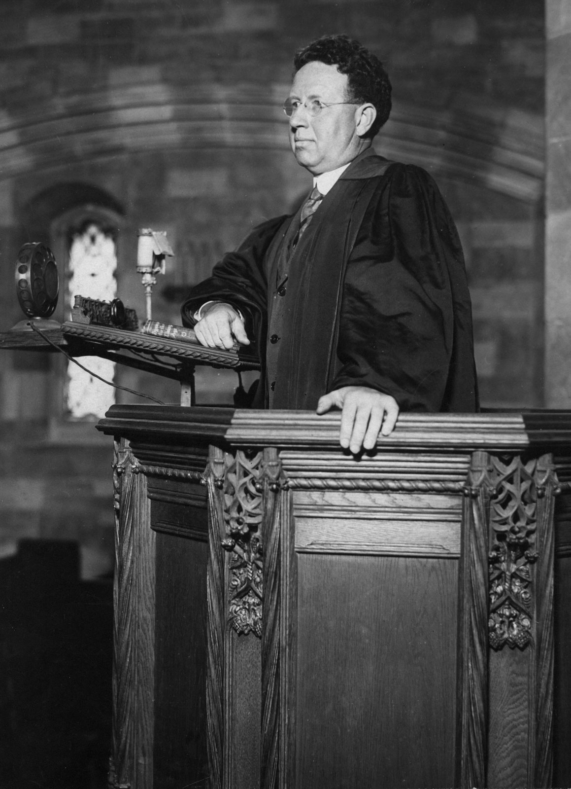 A black and white photograph of Harry Emerson Fosdick standing in a carved wooden pulpit