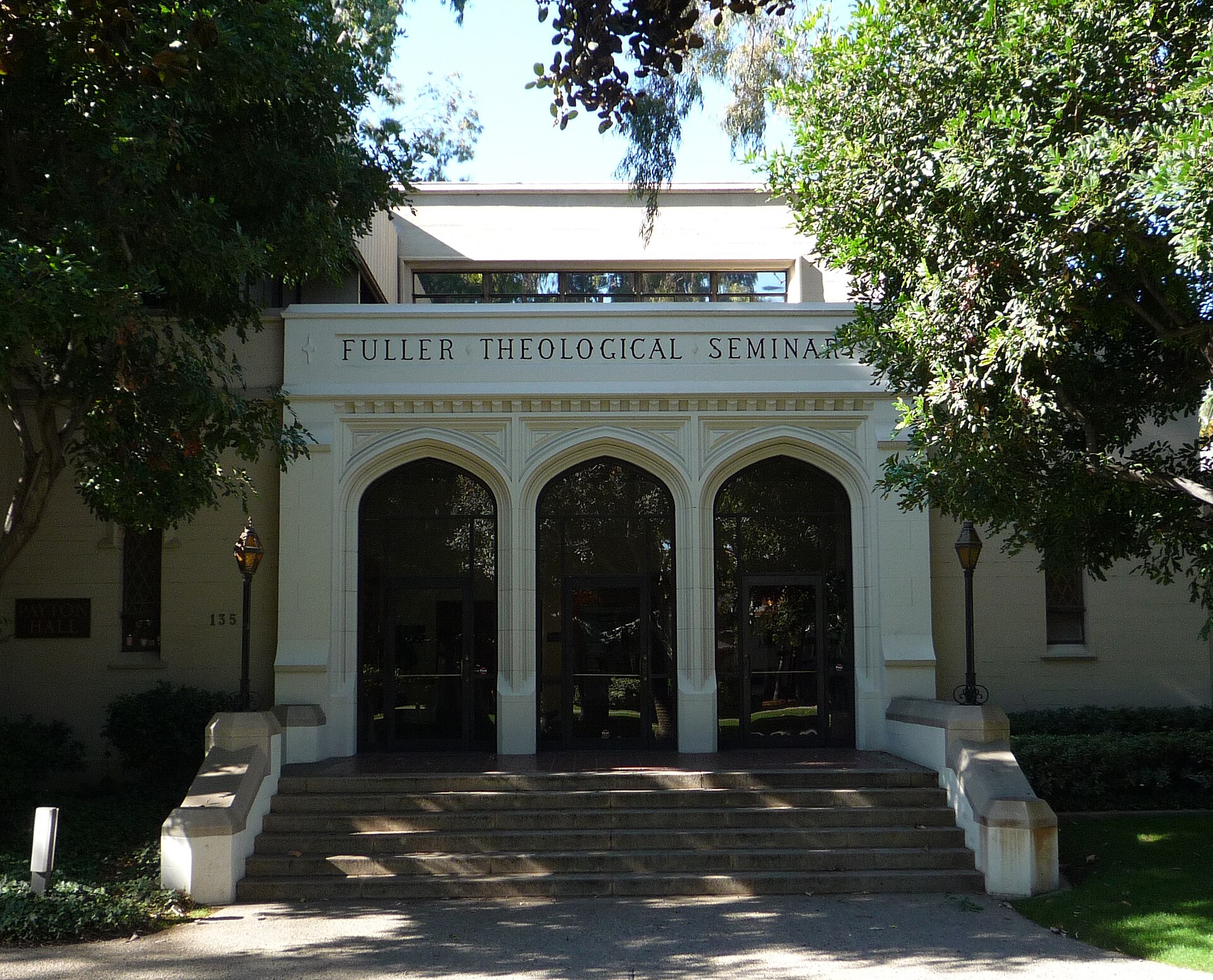 A low stone and stucco building, Payton Hall, with palm trees and a lawn on the campus of Fuller Theological Seminary in Pasadena