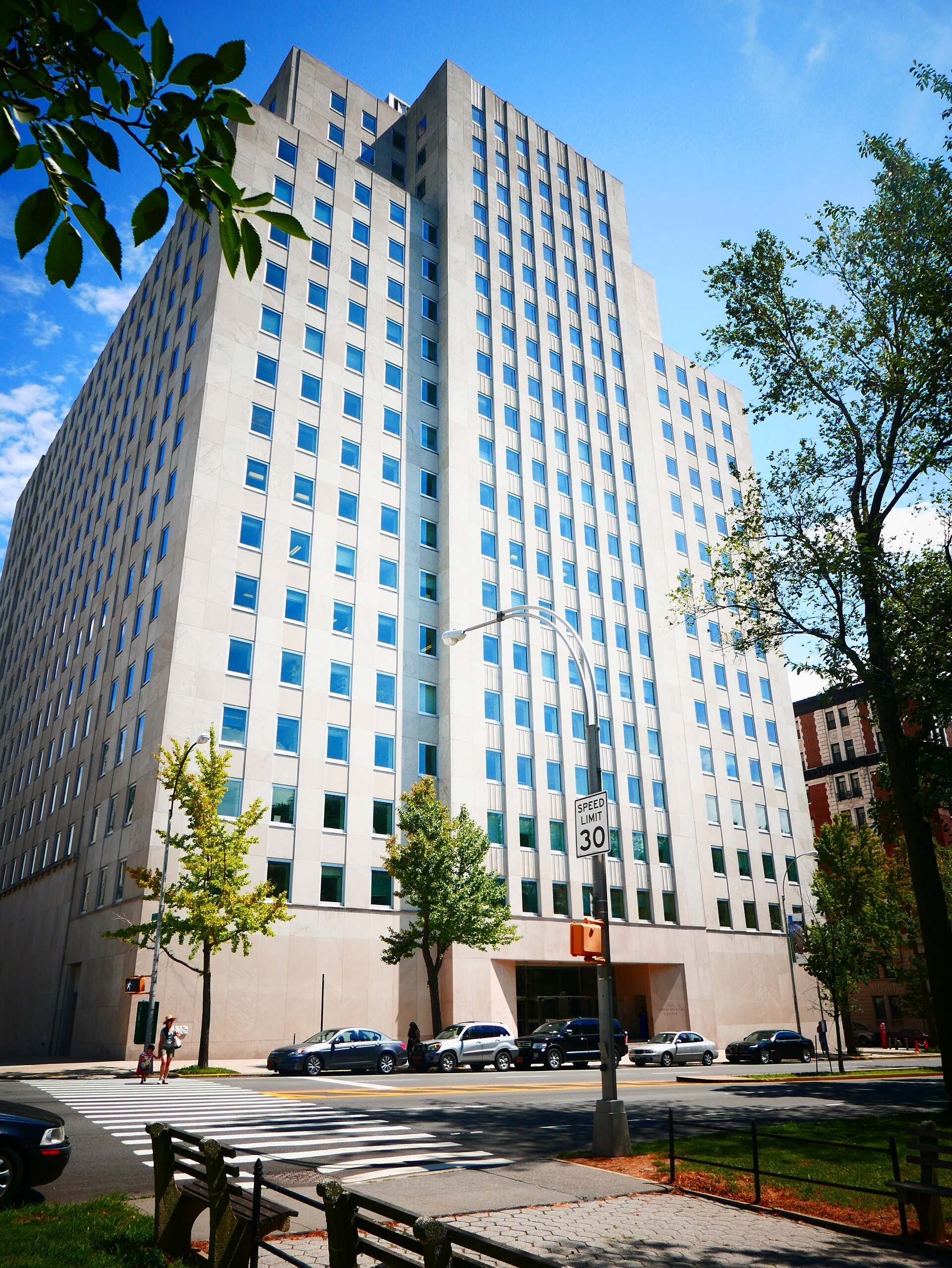 A tall pale stone office building on a tree-lined avenue, the Interchurch Center on Riverside Drive in Manhattan