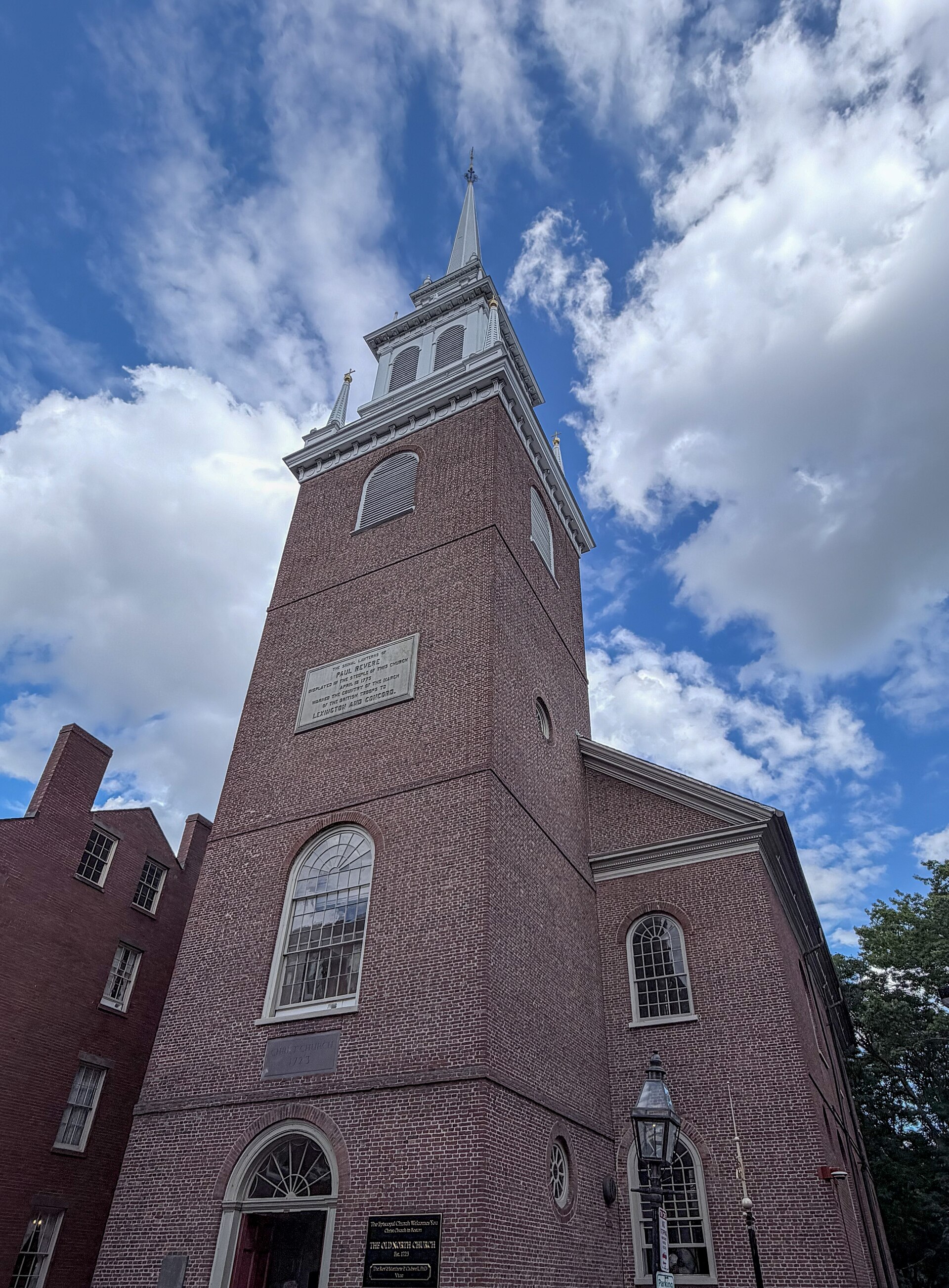 The tall white steeple and red brick tower of Boston's Old North Church seen from a narrow street