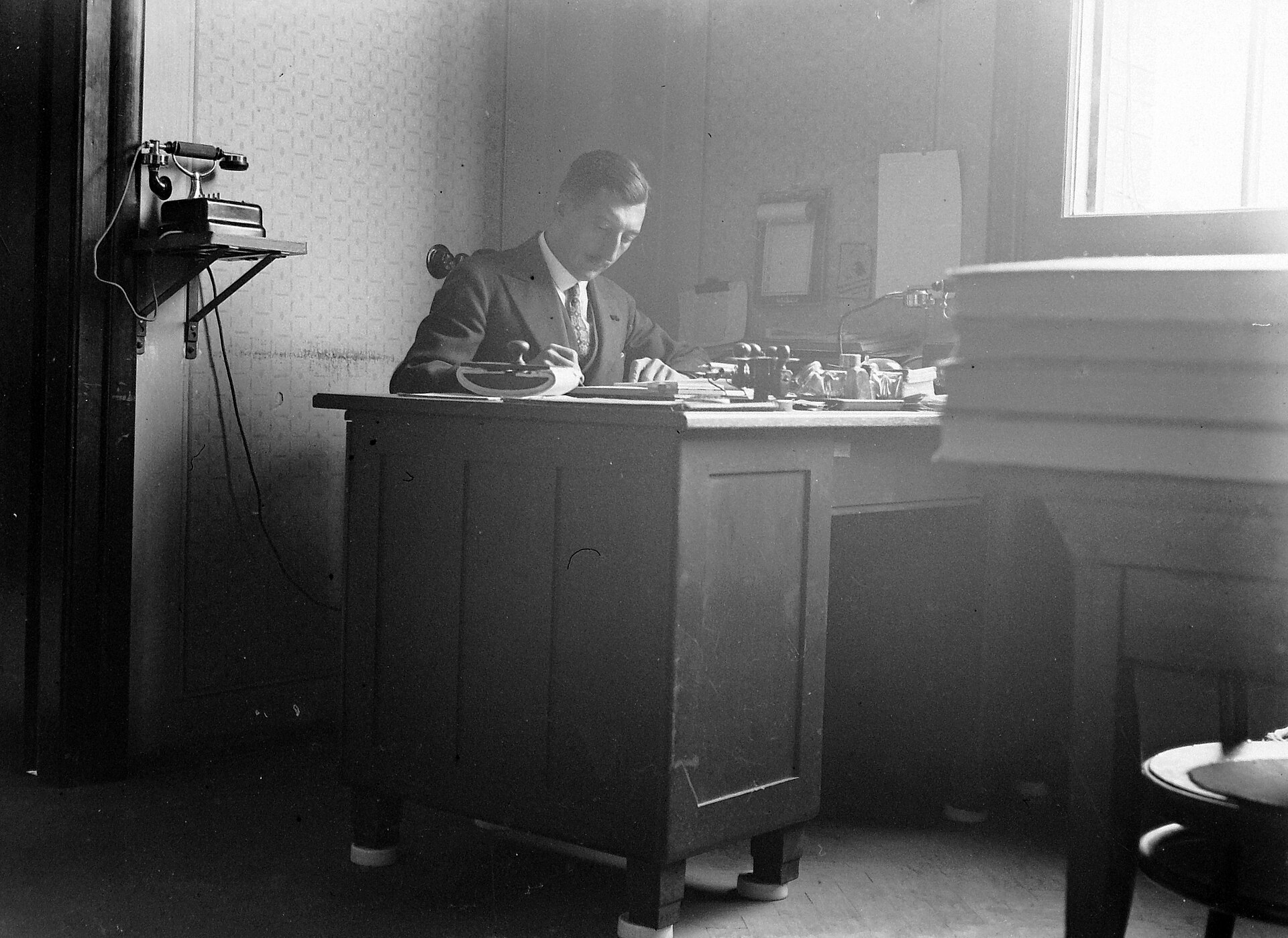 An office desk with a telephone, in a black and white photograph from about 1930