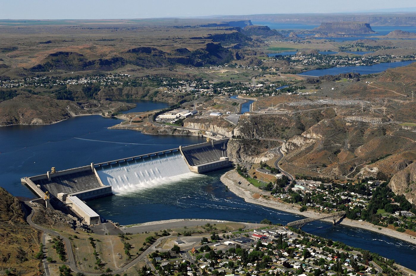 Aerial view of Grand Coulee Dam, a long concrete dam across the Columbia River with its reservoir behind it