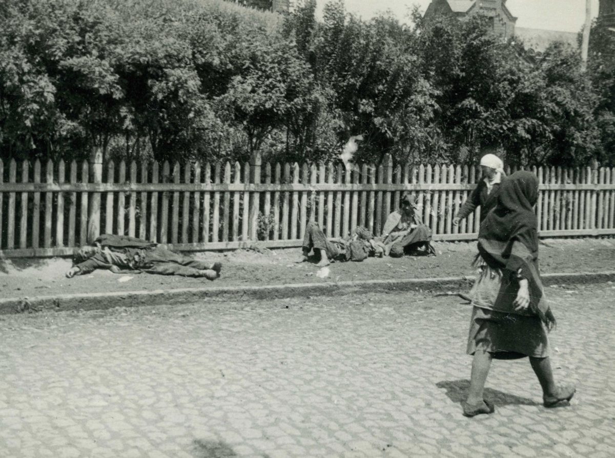 Black-and-white photograph of starving peasants lying and sitting on a city street in Kharkiv in 1933