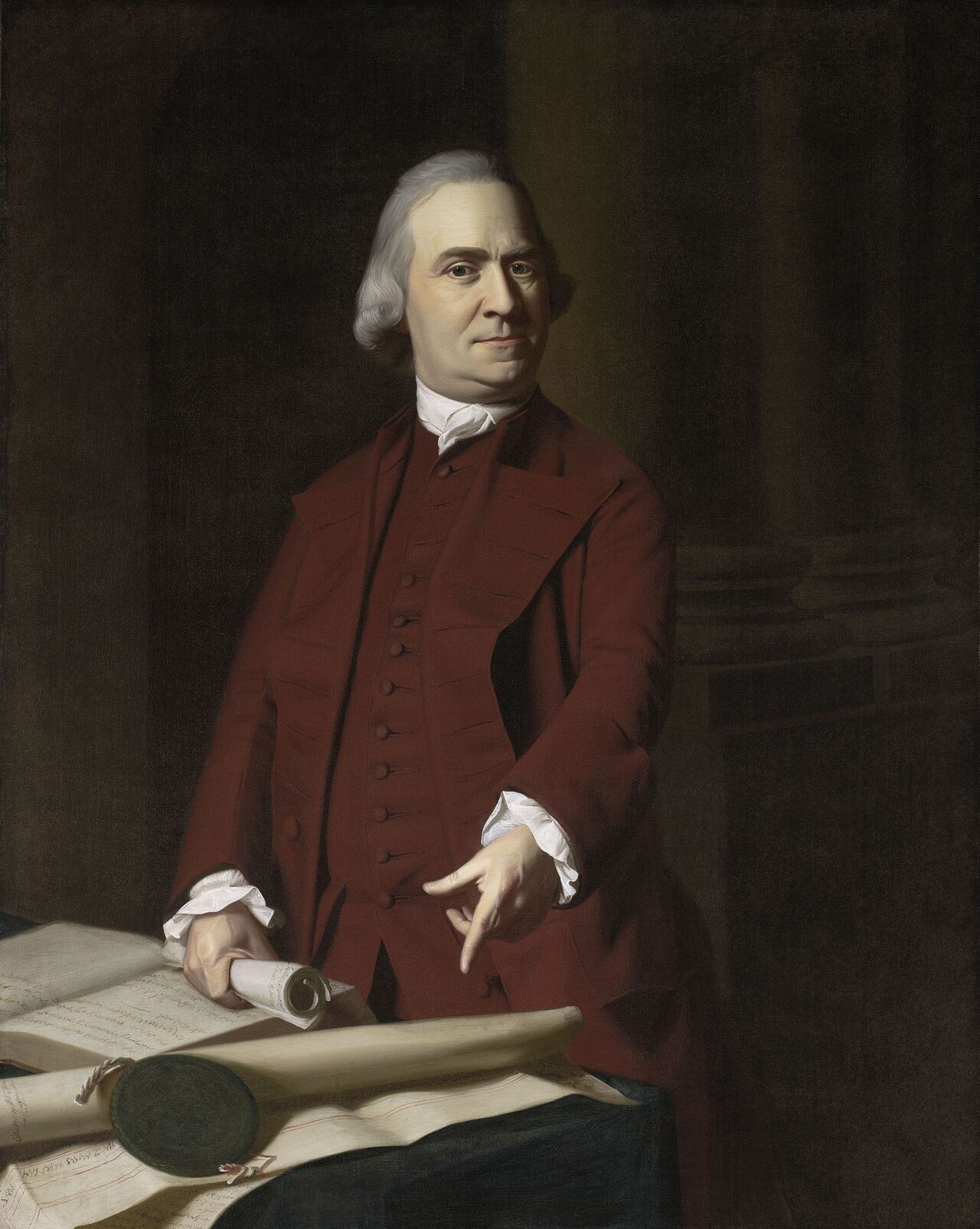 Oil portrait of Samuel Adams in a red coat, standing and pointing downward toward a document on a table