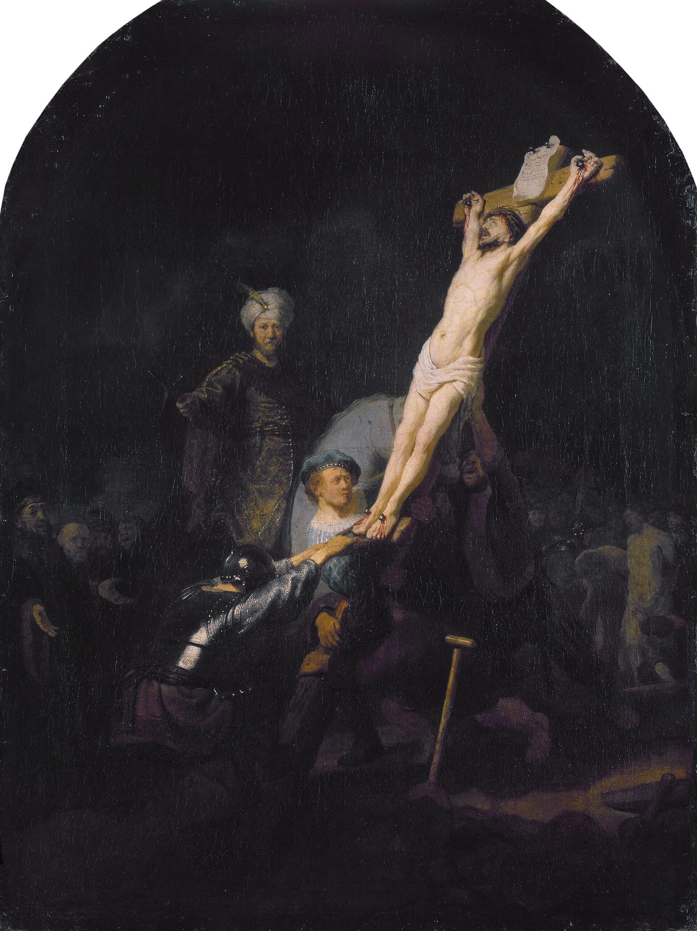Dark painting of Christ's cross being hauled upright by soldiers and workmen; one man in a blue beret, lit by the light on Christ's body, strains at the base