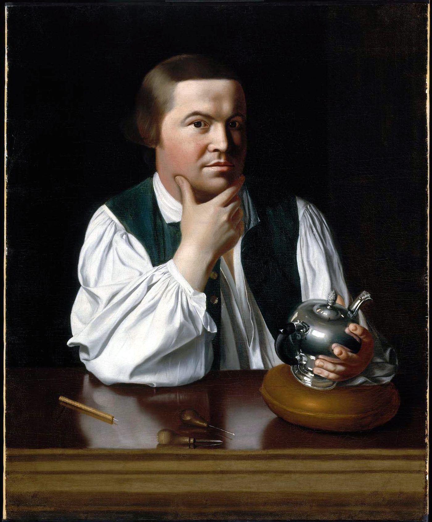 Portrait of Paul Revere seated at a polished table in a white shirt and open waistcoat, holding a silver teapot in one hand and resting his chin on the other
