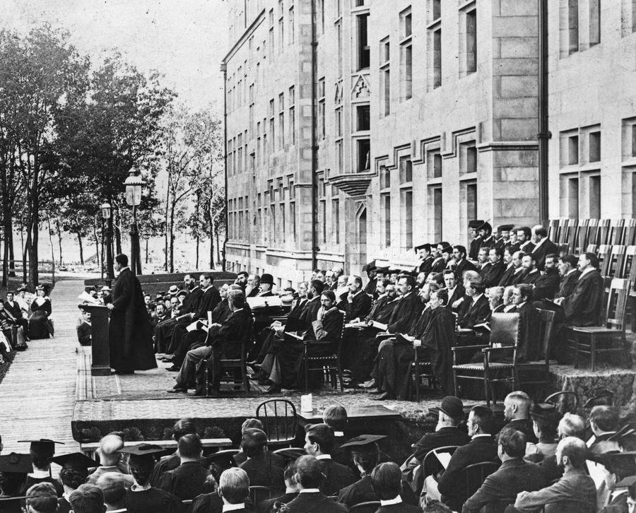 Faculty and trustees seated on a platform at the University of Chicago's seventh convocation in 1894 while Albert Michelson speaks