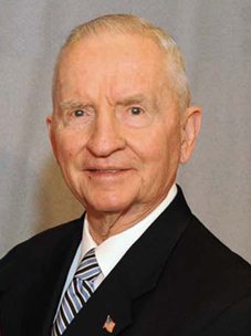 Ross Perot, white-haired and in a dark suit, speaking at an event of the Department of Veterans Affairs