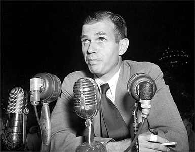 Black and white head-and-shoulders photograph of Alger Hiss, a slender man with dark hair, in a dark suit and tie