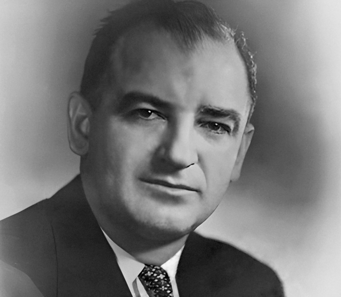 Studio portrait of a dark-haired man in a suit and tie