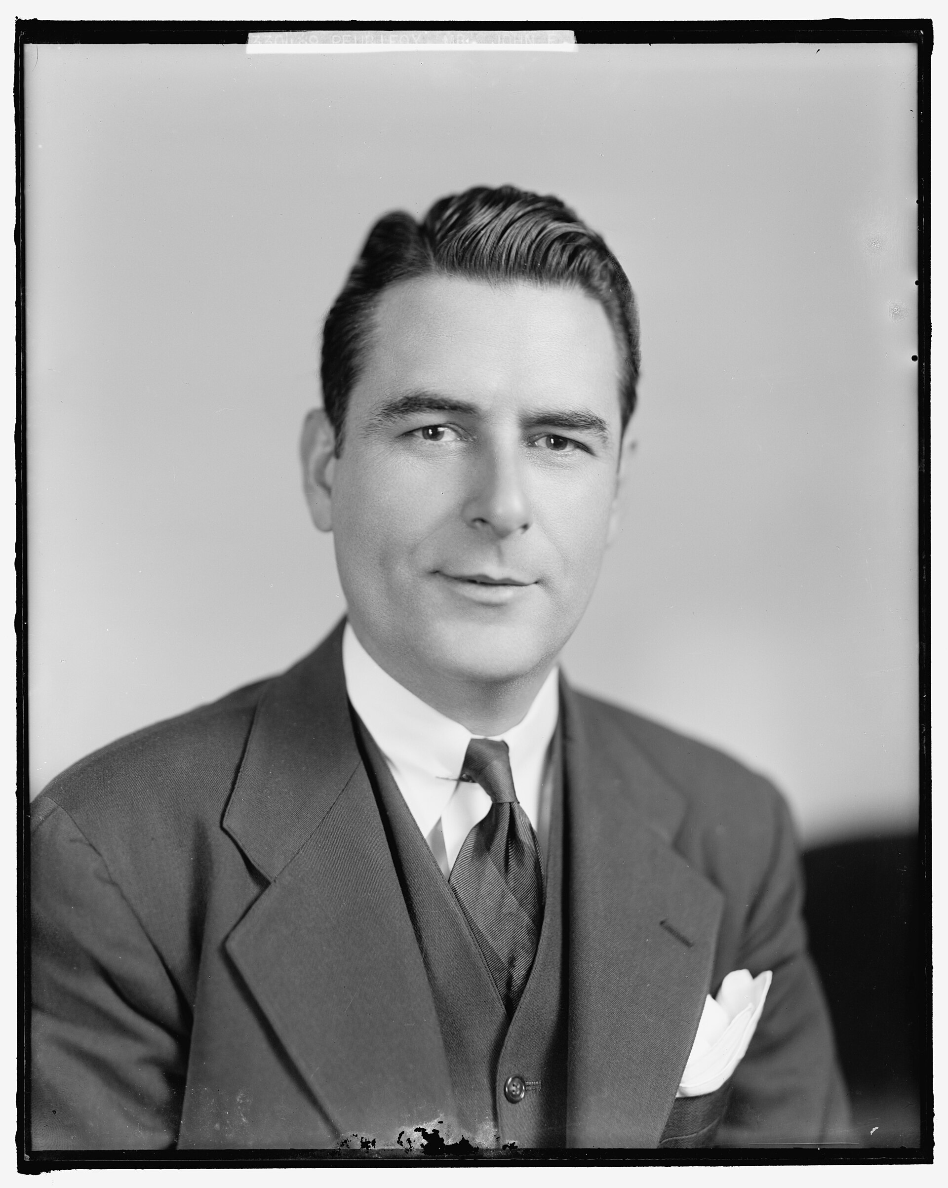 Black and white studio portrait of John E. Peurifoy in a suit and tie