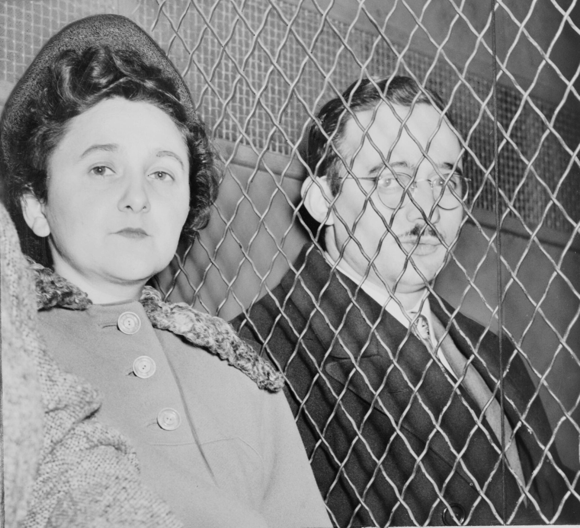 A man and a woman separated by a heavy wire mesh screen