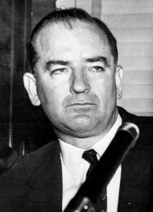 Black and white news photograph of Senator Joseph McCarthy in a dark suit and tie