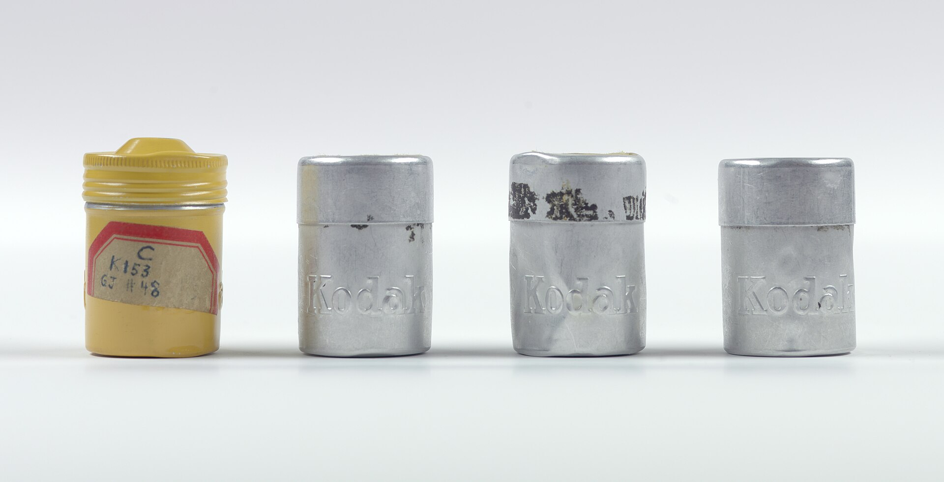 Small metal film canisters photographed as numbered exhibits, the containers that held the rolls of microfilm known as the Pumpkin Papers