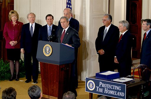 President George W. Bush speaking at a podium in the East Room of the White House at the signing of the Homeland Security Act